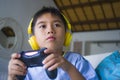 Oung hispanic little kid excited and happy playing video game online with headphones holding controller enjoying having fun sittin