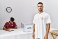 oung hispanic voter wearing vote badge standing at electoral center