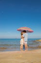 Oung lovers guy and girl on the seashore kiss under a large beach umbrella Royalty Free Stock Photo