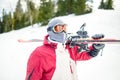 Oung man holding ski.Skier holding skis looking at the mountains.Side view of handsome skier man with mask and holding ski equipme