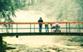 Young parents with baby in pram on bridge over flood river