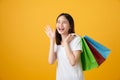 Oung smiling asian woman holding multi coloured shopping bags and announcing.