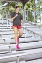 oung Woman running up and down bleacher stairs at a stadium training for her high school sports season.