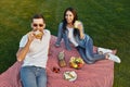 Ouple having small picnic with fruits and sandwiches