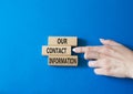 Our contact information symbol. Concept word Our contact information on wooden blocks. Businessman hand. Beautiful blue background Royalty Free Stock Photo