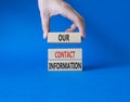 Our contact information symbol. Concept word Our contact information on wooden blocks. Businessman hand. Beautiful blue background Royalty Free Stock Photo