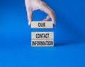 Our contact information symbol. Concept word Our contact information on wooden blocks. Businessman hand. Beautiful blue background Royalty Free Stock Photo