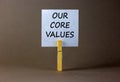 Our core values symbol. White paper with words `Our core values`, clip on wooden clothespin. Beautiful grey background. Business Royalty Free Stock Photo