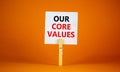 Our core values symbol. White paper with words `Our core values`, clip on wooden clothespin. Beautiful orange background. Busine Royalty Free Stock Photo