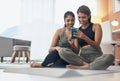Our goal is to inspire our followers. two young women looking at something on a cellphone while sitting at home in Royalty Free Stock Photo