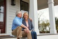 Our home is a part of our history. Portrait of a happy mature couple sitting on the doorstep of their home. Royalty Free Stock Photo