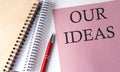 OUR IDEAS word on the pink paper with office tools on white background Royalty Free Stock Photo