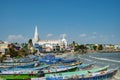 Our Lady of Ransom Shrine Church behind colorful houses on a sand beach occupied by fishing boats in Kanyakumari in India Royalty Free Stock Photo