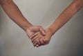 Our love is accepting. an unrecognizable couple standing together against a grey wall indoors and holding hands. Royalty Free Stock Photo