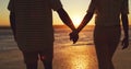 Our love is deeper than the ocean. Rearview shot of an unrecognizable young couple holding hands on the beach at sunset. Royalty Free Stock Photo