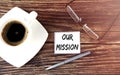 OUR MISSION text on sticky with coffee,pen and glasses on the wooden background Royalty Free Stock Photo