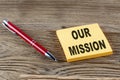 OUR MISSION text on sticky with pen on the wooden background Royalty Free Stock Photo