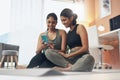 Our page has so many followers already. two young women looking at something on a cellphone while sitting at home in Royalty Free Stock Photo