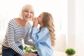 Our secret. Adorable girl whispering to grandmother