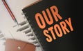 Our Stroy words written on a cover, of copybook, orange on black. Business story concept. Selective focus