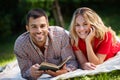 Our time together is always perfect. Portrait of a happy young couple reading a book while lying on the grass in a park. Royalty Free Stock Photo