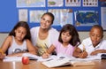 Our youth will write our future. A young teacher sitting with her three ethnic pupils while they study - portrait.