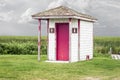 Out door unisex toilet for man and woman with a pink door.