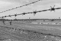 Out of focus barbed wire fence and destroyed barracks at concentration camp Auschwitz II - Birkenau, Poland. Royalty Free Stock Photo