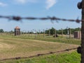 Out of focus barbed wire fence in the foreground with watch tower in the background in concentration camp Auschwitz II - Birkenau. Royalty Free Stock Photo