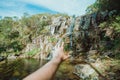 Out of focus hand trying to reach a waterfall in a inspirational image