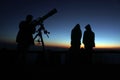 Out of focus image of silhouette of people with telescope on the mountain at the sky sunrise. Image contain certain grain or noise Royalty Free Stock Photo