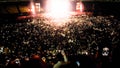 Out of focus image of big crowd of fans sitting on stadium seats watching and listening rock concert at night. Royalty Free Stock Photo