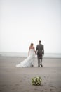 Out of focus and unrecognizable bride and groom walking away on the beach Royalty Free Stock Photo