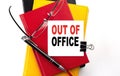 OUT OF OFFICE text written on a sticky on colorful notebooks