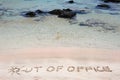 OUT OF OFFICE written on sand on a beautiful beach, blue waves in background Royalty Free Stock Photo