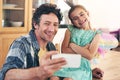 She out-selfies me every time. a happy father and daughter taking a selfie together on a mobile phone at home. Royalty Free Stock Photo