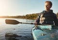 Out on the water where he longed to be. a young man kayaking on a lake outdoors.