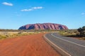 Outback, Australia - November 12, 2022: Road to the iconic landmark of Australian outback. The red rock of the Uluru or Ayres rock Royalty Free Stock Photo