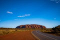 Outback, Australia - November 12, 2022: Road to the iconic landmark of Australian outback. The red rock of the Uluru or Ayres rock Royalty Free Stock Photo