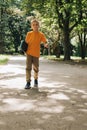 Outdoor activities for children. An upset young boy in sunglasses stay with a skateboard in a public park Royalty Free Stock Photo