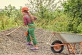 Outdoor activity. girl who is transporting rubble in a wheelbarrow. construction work. girl builder takes a shovel of Royalty Free Stock Photo