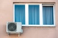 An outdoor air conditioner unit installed on the wall of a residential building next to the window. Installation, repair and