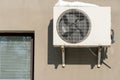 An outdoor air conditioner unit installed on the wall of a residential building next to the window. Installation, repair and