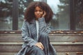 Outdoor autumn photo of young thoughtful african american woman sitting on wooden stairs on fall day Royalty Free Stock Photo