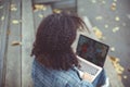 Outdoor autumn portrait of young cheerful african american woman with laptop on knees sitting on wooden house stairs Royalty Free Stock Photo