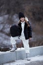 Outdoor autumn portrait of young fashionable happy girl wearing black coat, hat, with black backpack, posing in street of European Royalty Free Stock Photo