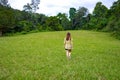 Outdoor of back portrait of lonely woman in green field. Young woman walking in meadow with copy space