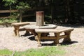 Outdoor backyard wooden homemade benches around strong wooden table surrounded with gravel and uncut grass