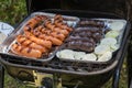 Outdoor barbecues. Sausages, black pudding, onions and baked bread on the grill. Food baked on aluminum foil tray