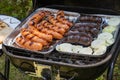 Outdoor barbecues. Sausages, black pudding, onions and baked bread on the grill. Food baked on aluminum foil tray